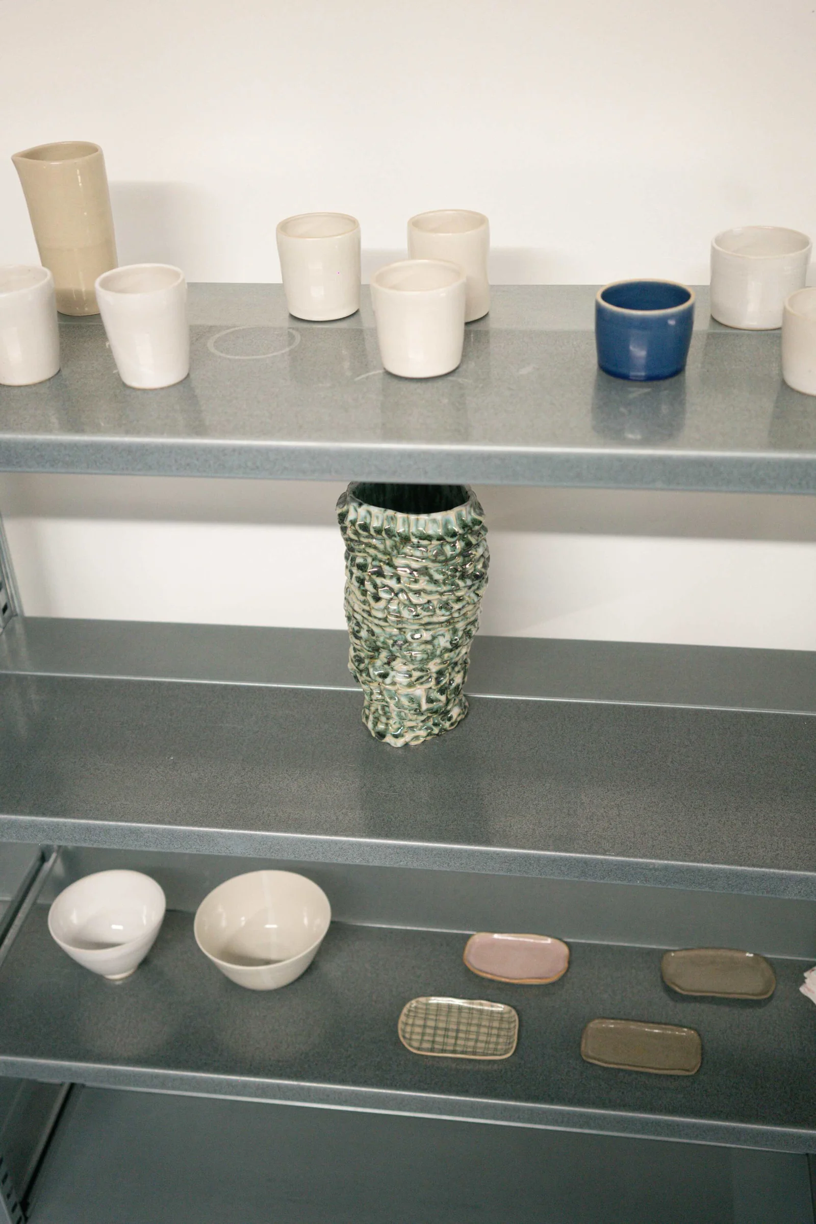 Colourful handmade ceramics on a studio shelf