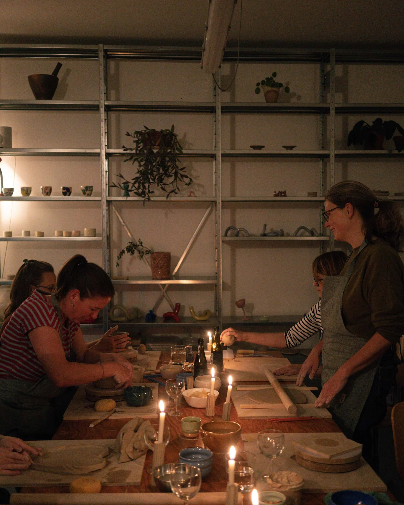 A candlelit evening pottery session around a long wooden table in Zürich