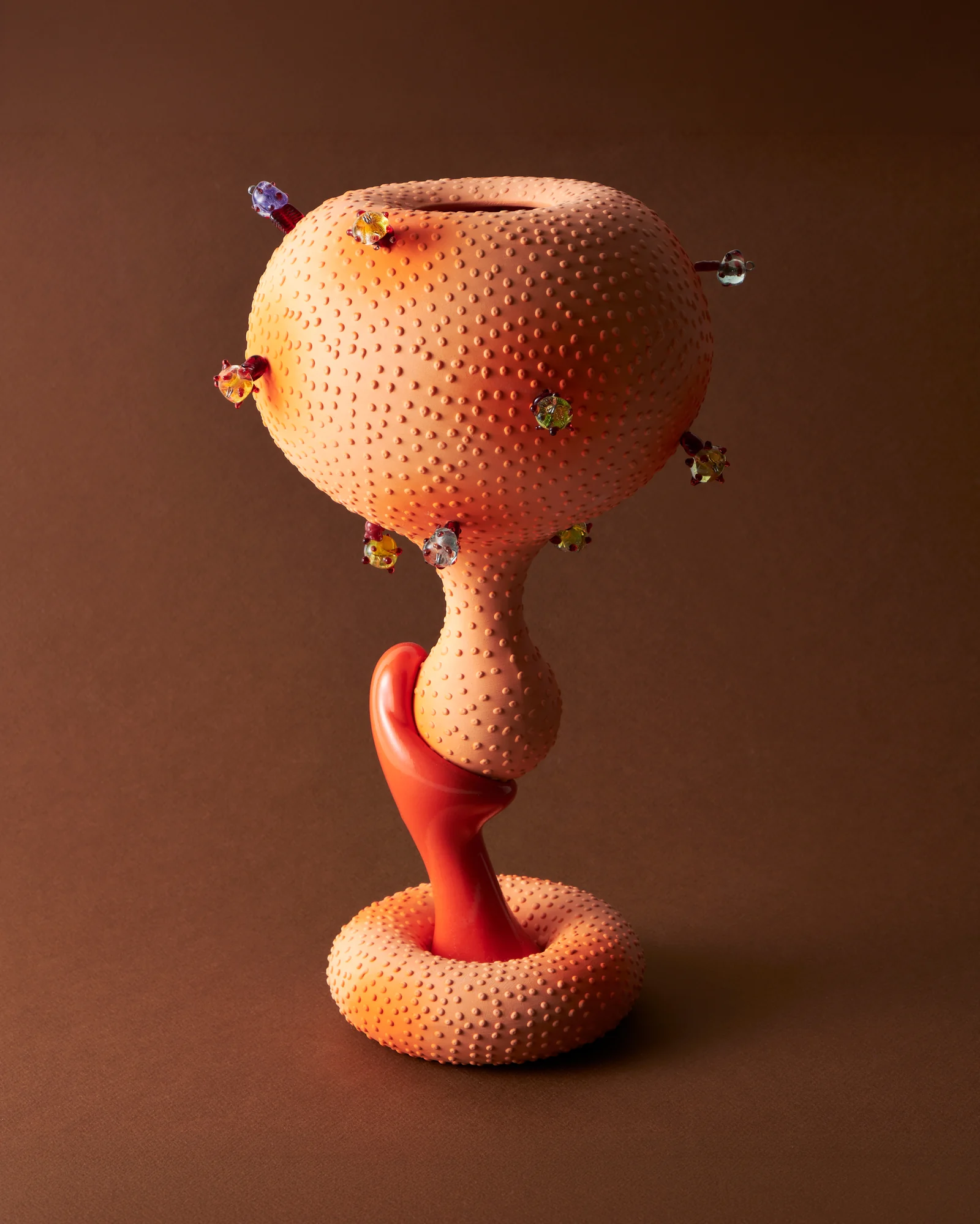 A dotted coral porcelain goblet by Jihyun Kim, set with colourful glass beads