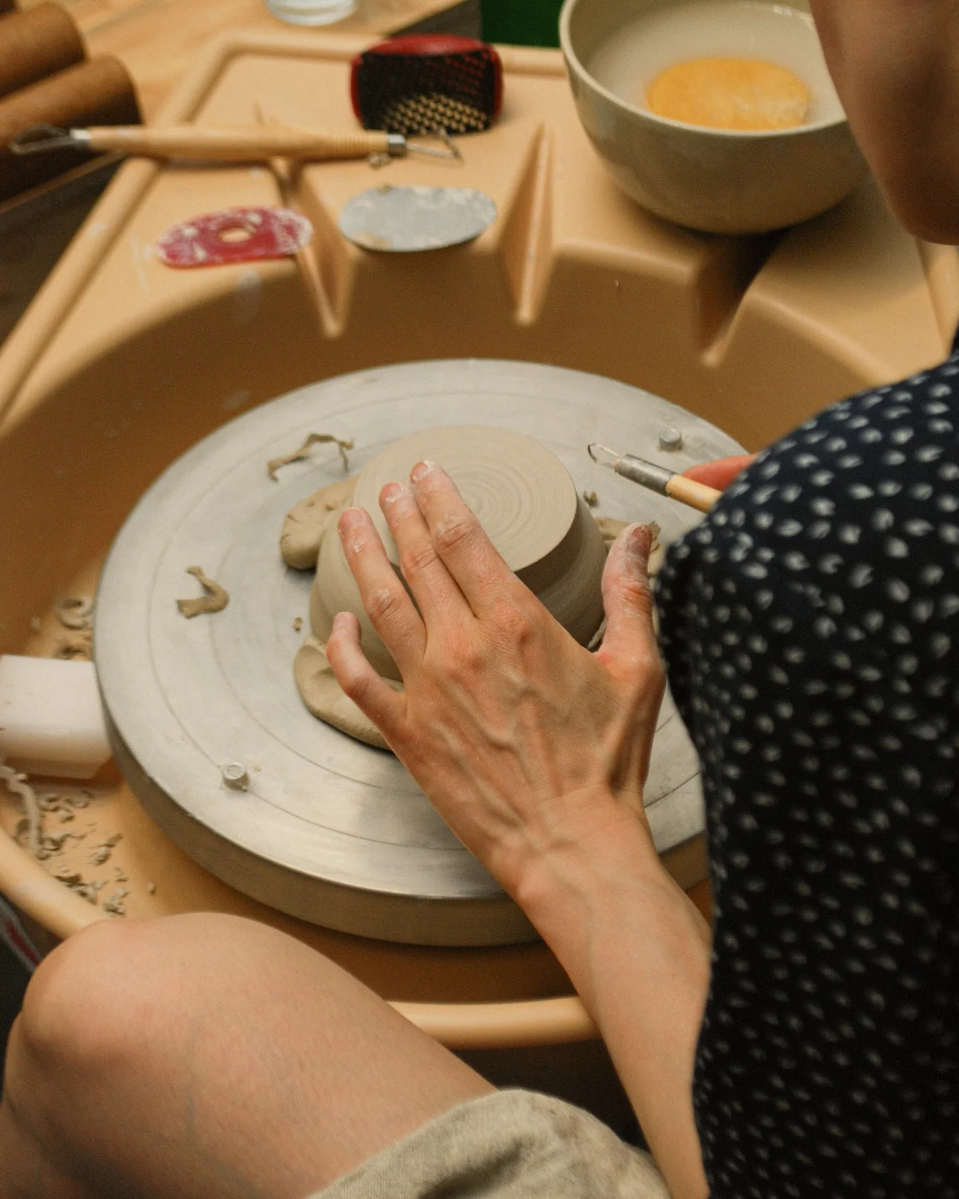 A participant refining the base of a clay bowl on a pottery wheel