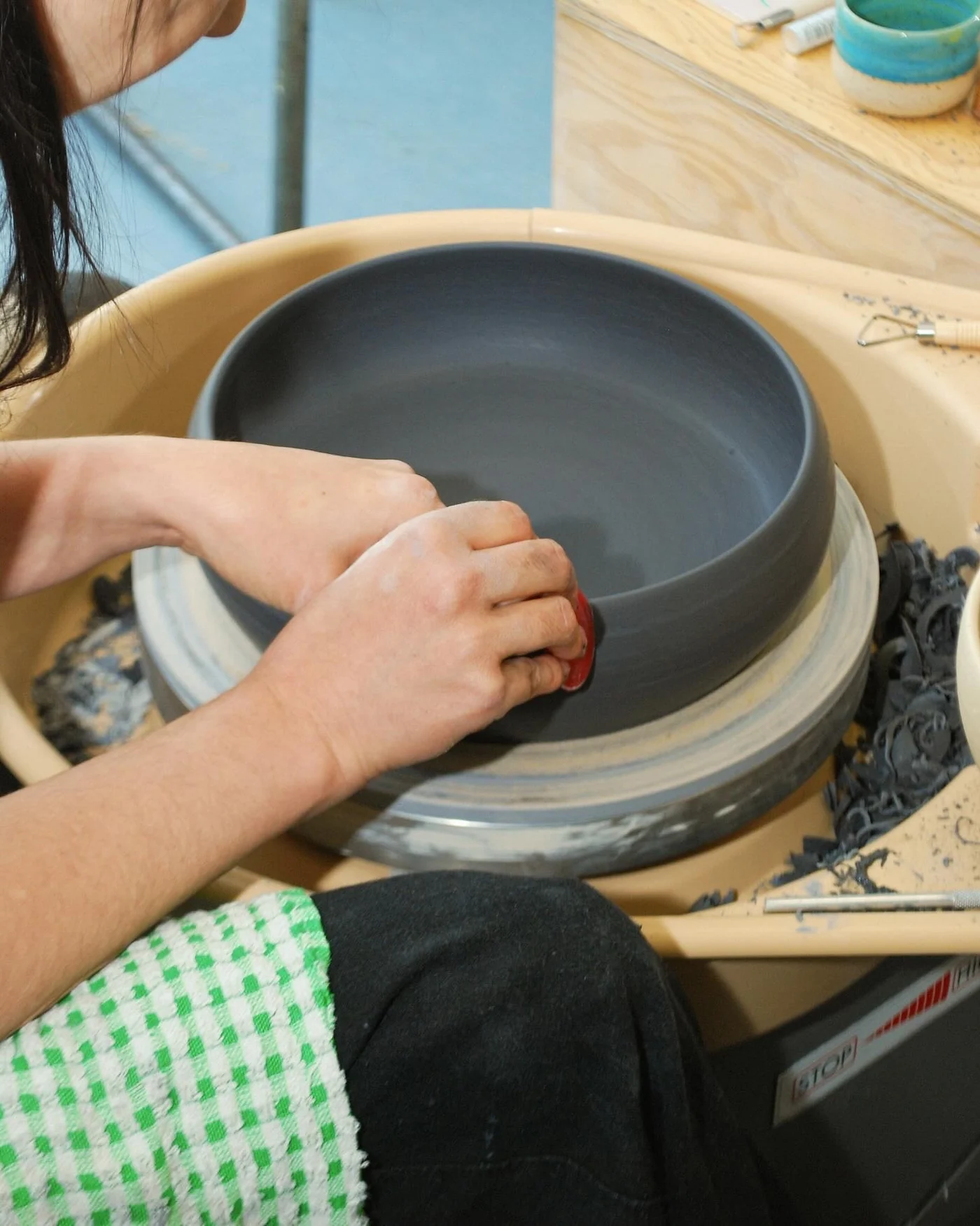 Close-up of hands smoothing the interior of a large ceramic bowl on a wheel